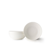 A set of four Adam Liaw Everyday Noritake medium white porcelain bowls. One bowl is propped on its edge while the other three are stacked beside it against a white background.
