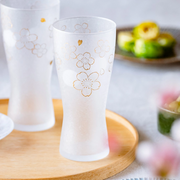 Aderia Sakura beer glass elegantly displayed on a wooden tray with food in the background.

