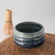 Ao Unofu Japanese Matcha Bowl with a milky blue and white glaze, shown with a bamboo tea whisk resting inside.
