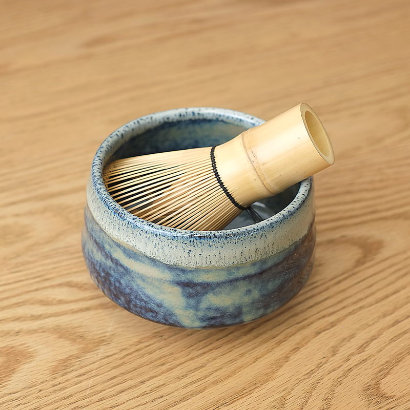 Ao Unofu Japanese Matcha Bowl with a milky blue and white glaze, shown with a bamboo tea whisk resting inside.