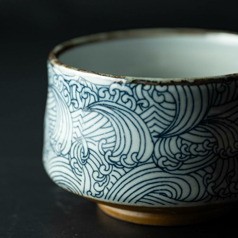 A close-up detail of the Arahami matcha bowl, showing the intricate blue and white 'wild wave' pattern and dark rim.