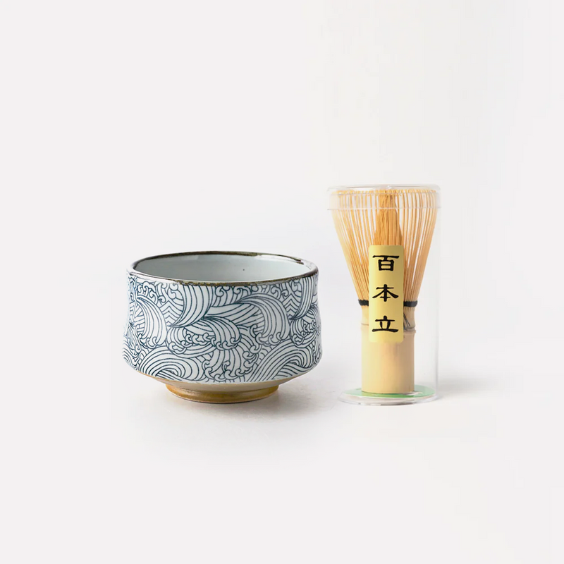 The Aranami Japanese matcha bowl and whisk set, featuring a ceramic bowl with a blue 'wild waves' pattern and a traditional bamboo whisk (chasen).
