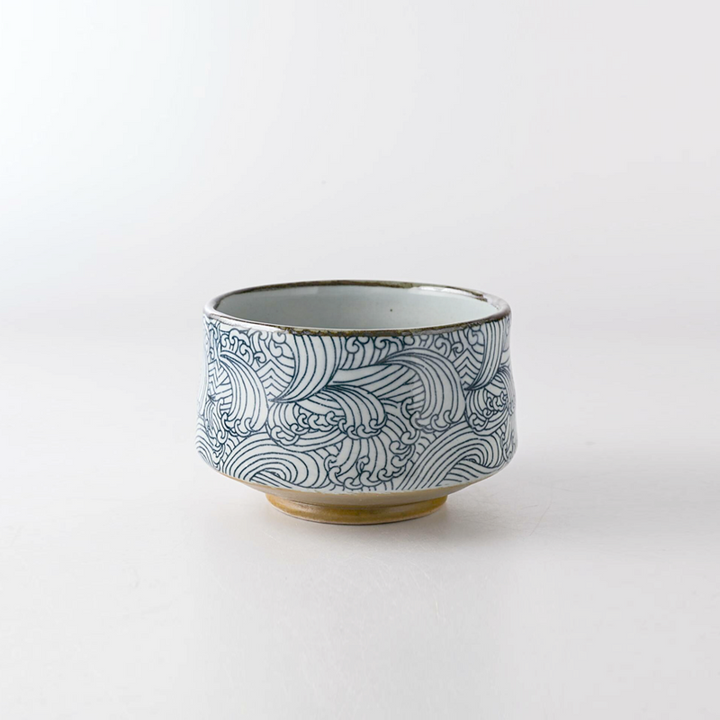 A side view of the Arahami Japanese matcha bowl, showing the full 'wild wave' pattern and unglazed foot against a white background.
