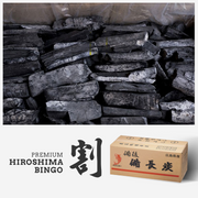 A stack of Premium Hiroshima Bingo Binchotan charcoal sticks resting on a smooth wooden plank against a white background.