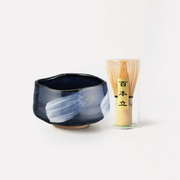 A studio shot of the Blue Glaze Matcha Bowl and a 100-prong bamboo whisk (chasen) set on a white background.