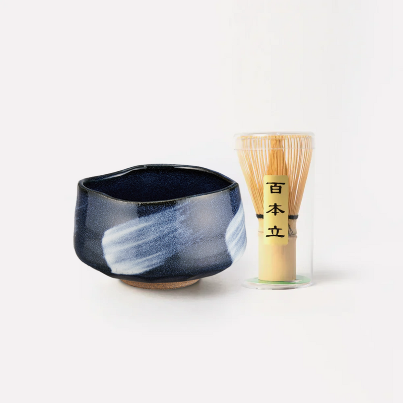 A studio shot of the Blue Glaze Matcha Bowl and a 100-prong bamboo whisk (chasen) set on a white background.