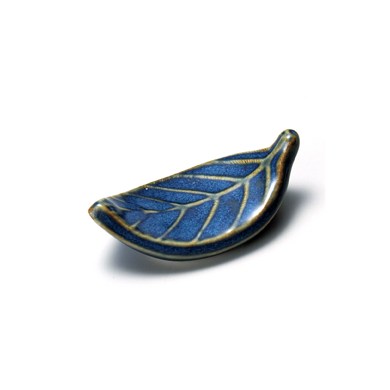 Elegant porcelain chopstick rest shaped like a leaf, adorned with deep blue patterns.