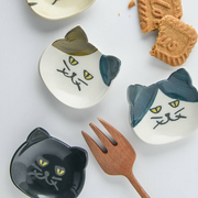 Collection of Japanese cat cutlery rests in various colours displayed with cookies and a wooden fork illustrating versatility and decorative use
