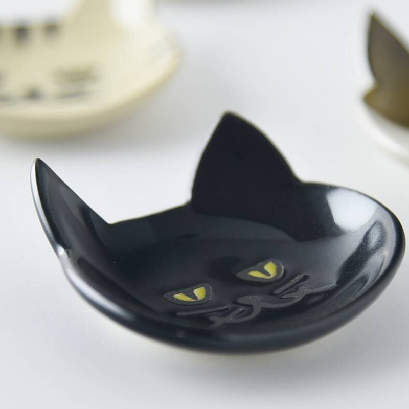 Black Japanese cat cutlery rest placed next to white counterparts to contrast its unique glossy black finish and design details





