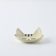 Side view of a cream-coloured Japanese cat cutlery rest showcasing its curved design
