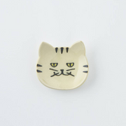 Cream-coloured Japanese cat cutlery rest with subtle facial details on a plain background
