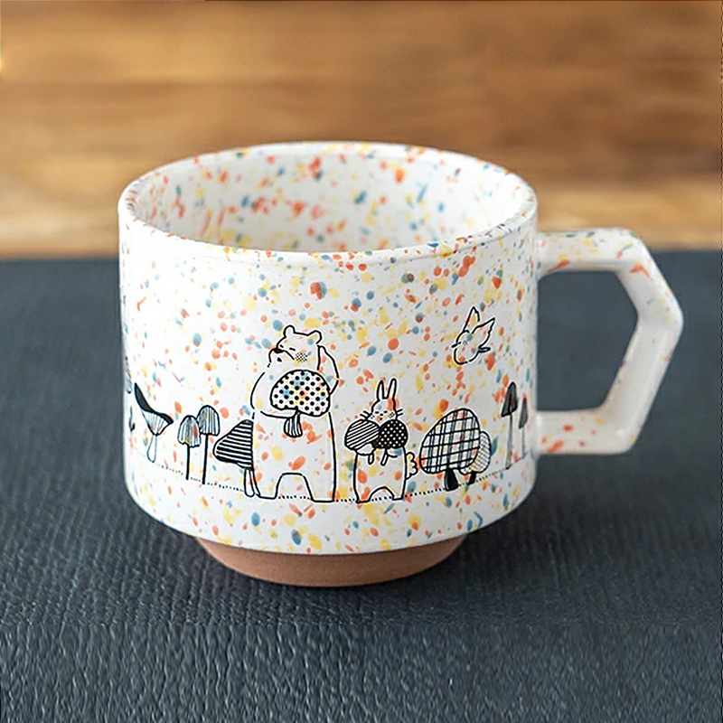 A white CHIPS stackable mug featuring colourful splashes and a whimsical black line drawing of a bear and rabbit holding mushrooms, part of the Mori no Kinoko Club collection.