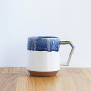 The CHIPS Stack Mug in the White Navy Drop colour, showing its unique angular handle and textured blue glaze over a white and terracotta base.