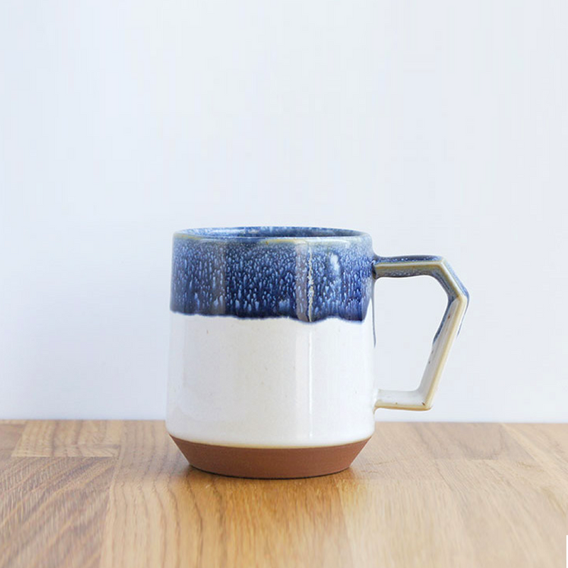 The CHIPS Stack Mug in the White Navy Drop colour, showing its unique angular handle and textured blue glaze over a white and terracotta base.