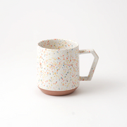 The CHIPS Stack Mug in the Splash White Orange colour, showing its colourful terrazzo-style splatter and unique angular handle.