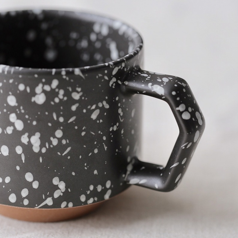 A close-up detail shot of the CHIPS mug's unique angular handle and the white-on-black splatter glaze.