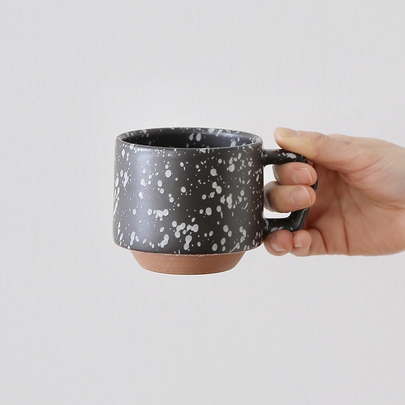 A hand holding the 280ml CHIPS Stack Mug in Splash Black White to show its size and ergonomic grip.