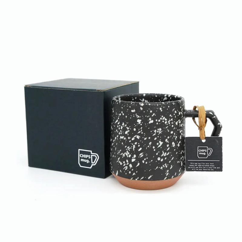 The 380ml CHIPS Stack Mug in Splash Black White shown next to its elegant black gift box, with a branded tag on the handle.