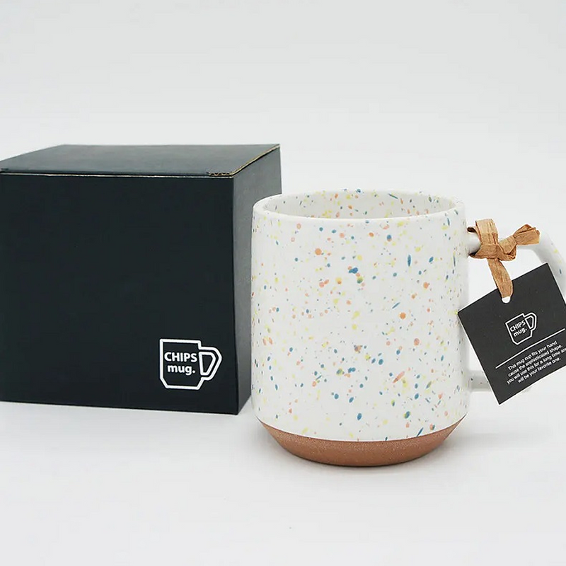 The CHIPS Stack Mug in the Splash White Orange colour, showing its colourful terrazzo-style splatter and unique angular handle.