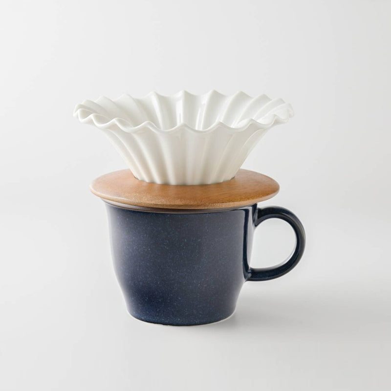 Chill Out ruffled white ceramic coffee dripper on an acacia holder atop a navy mug