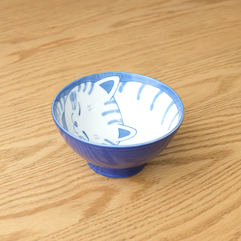 Daitoua Neko Chigura Dora Rice Bowl featuring a blue and white illustration of a sleeping tabby cat with striped patterns curled up inside the bowl.