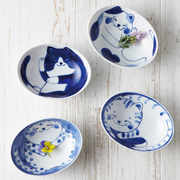 A collection of Daitoua Neko Chigura tableware featuring various cat illustrations, including oval serving bowls, plates, and small sauce dishes. The hand-painted blue and white designs showcase adorable cats in different playful poses.