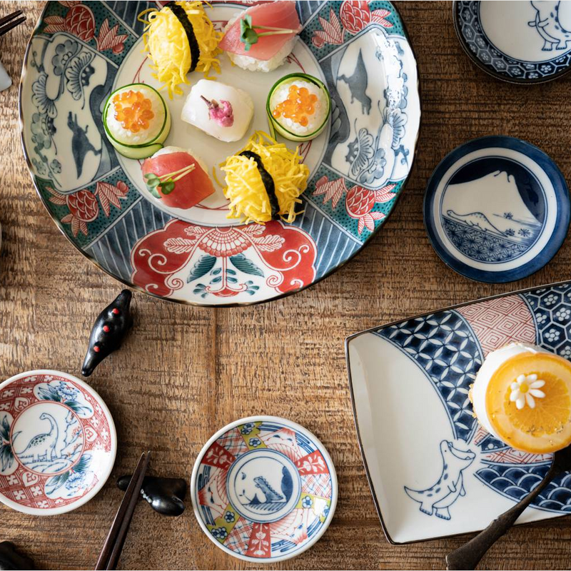 The Edokko Dinosaur dinner plate shown as part of a full tableware set, arranged for a Japanese meal on a wooden table.

