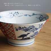 Edokko Dinosaur Donburi Bowl held in hand, featuring traditional plum blossom and bird patterns in blue and red.