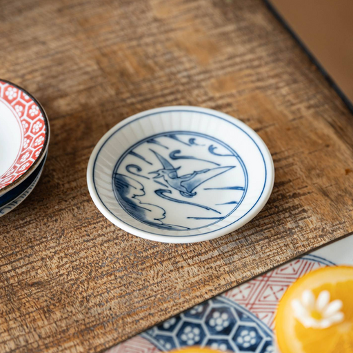 A lifestyle setting featuring the Edokko Dinosaur Hiyakuryu mini plate on a wooden table, displayed alongside other patterned dishes.