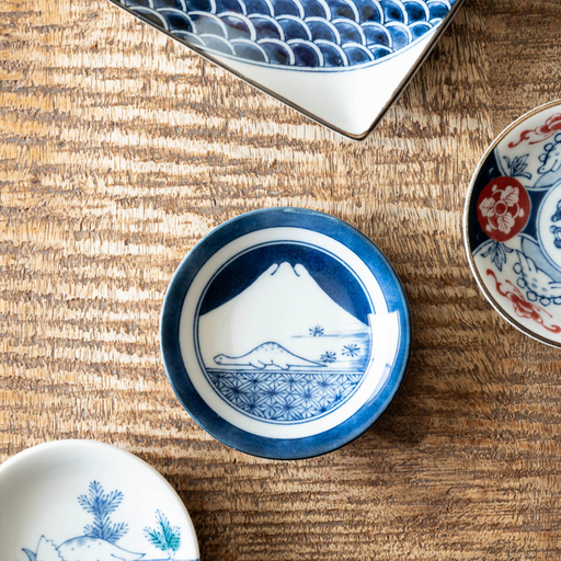 The Edokko Dinosaur Mount Fuji mini plate displayed on a wooden table alongside other plates from the series.

