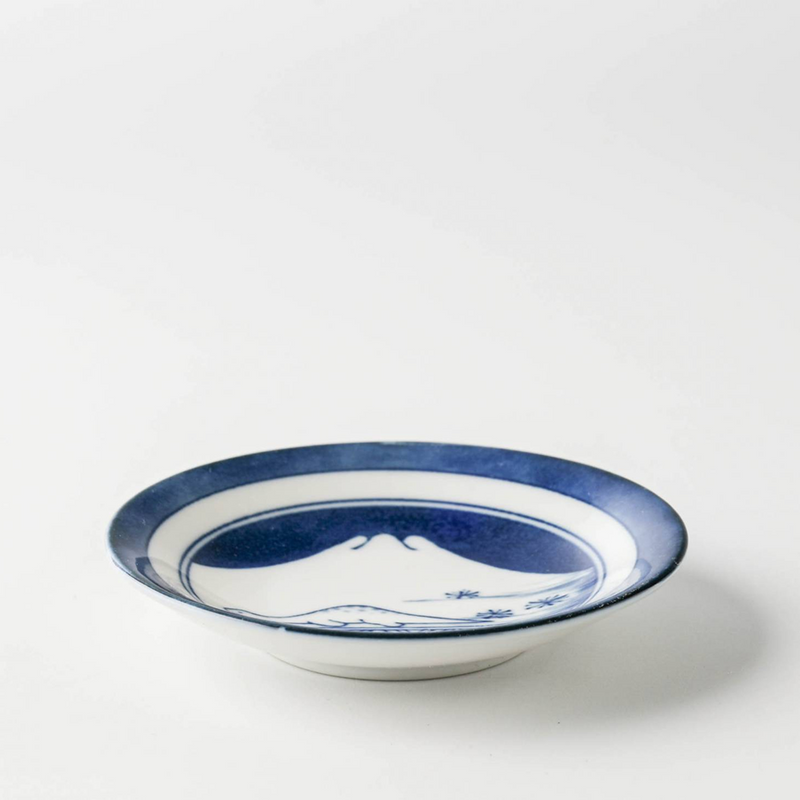An angled view of the Edokko Dinosaur Mount Fuji mini plate, showing its blue and white design and shape.

