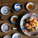 Several mini plates, each with unique Japanese-inspired dinosaur designs, used to serve soy sauce alongside sushi dishes. The setup is on a wooden surface, showcasing a delightful, traditional Japanese presentation.

