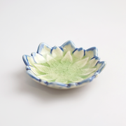 
An angled product image of the green Fiore Dahlia mini plate, showing its flower shape and light green and blue crackled glaze.

