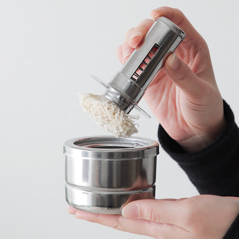 Freiz Stainless Steel Oil Basting Set with a removable brush, held by hand for demonstration.
