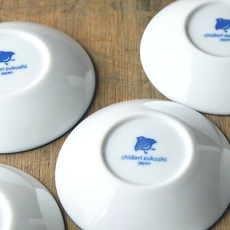 The white underside of several side plates, each featuring a blue bird logo that reads chidori zukushi Japan.
