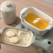 The Fuji deep fryer in use on a portable stove, with food being breaded in one tray and fried in the main pot.