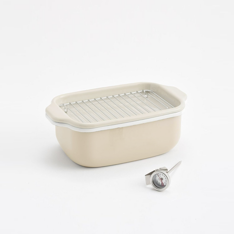 The Fuji enamel deep fryer pot with the wire draining rack inside, shown next to the included clip-on thermometer.