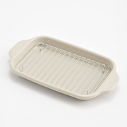 The wire draining rack resting inside the shallow tray, used for letting oil drip from fried foods.