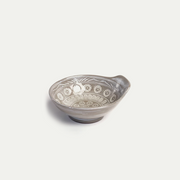 A studio photo of the Ginpo Hana Mishima donabe bowl, showcasing its grey clay body, white inlaid flower pattern, and side handle.