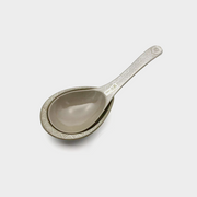 The Ginpo Hana Mishima clay soup ladle resting on its matching clay ladle rest, showing the rustic, earthy texture of the ceramic.