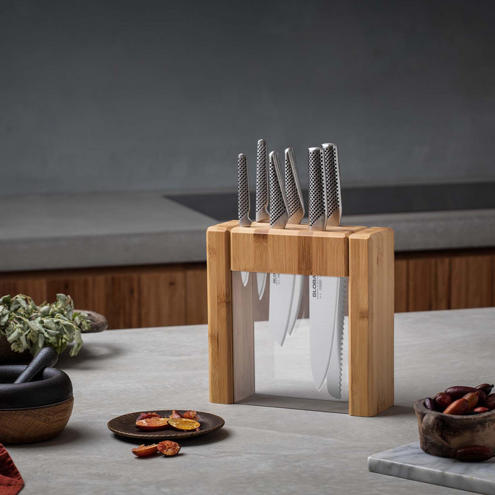 Global Ikasu 7-piece knife set in a bamboo knife block, displayed in a modern kitchen setting.