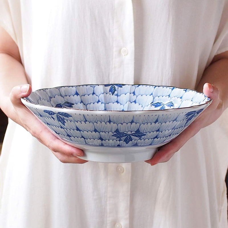 Hana Manyo large Japanese serving bowl in blue and white porcelain with a dense chrysanthemum floral and leaf pattern in deep indigo, shown held in two hands to illustrate the generous 25cm scale.