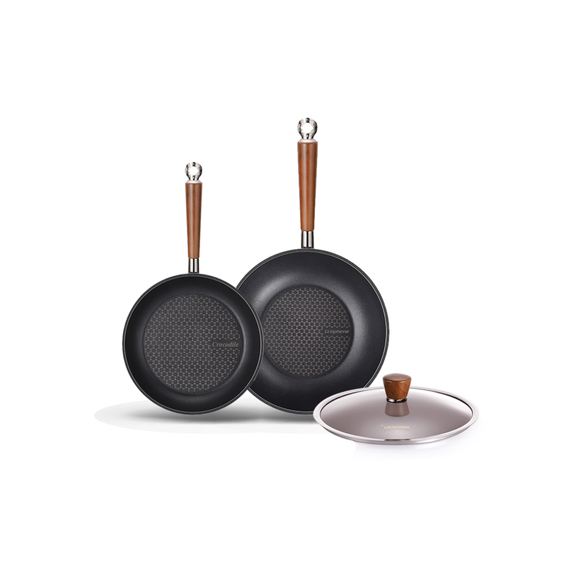 The 3-piece Happycall Crocodile Graphene nonstick induction set, including a 24cm frypan, 28cm wok, and a 28cm glass lid, all with wood-style handles.

