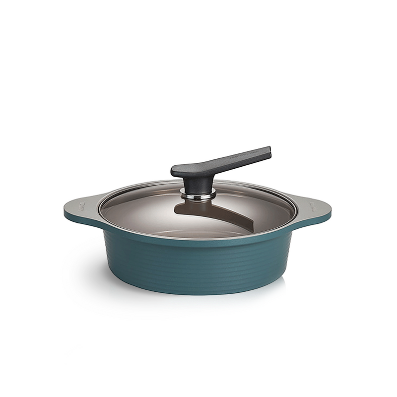 The low 24cm Happycall Onde ceramic nonstick induction pot in an ocean green finish, shown with its self-standing tinted glass lid and featuring a ridged exterior.
