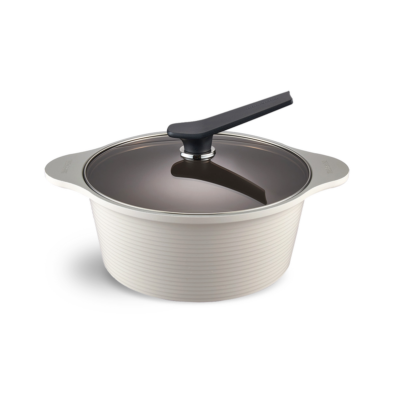 The 28cm Happycall Onde ceramic nonstick induction stockpot in an ivory finish, shown with its self-standing tinted glass lid and featuring a ridged exterior.
