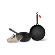 The Happycall Noire Titanium Plus cookware set, featuring a 26cm frypan, a 26cm wok, and a tinted glass lid, all with textured black surfaces and dark wood-style handles.







