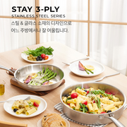 A lifestyle image of the Happycall Stay 3-Ply Stainless Steel Series, showing a frypan and sauté pan filled with delicious food on a dining table setting.

