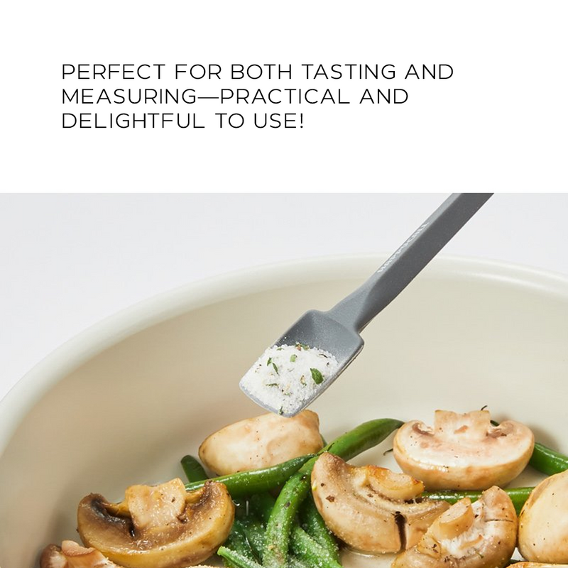 A small grey silicone spatula scooping seasoned salt from a bowl of sautéed mushrooms and green beans, illustrating practical use.

