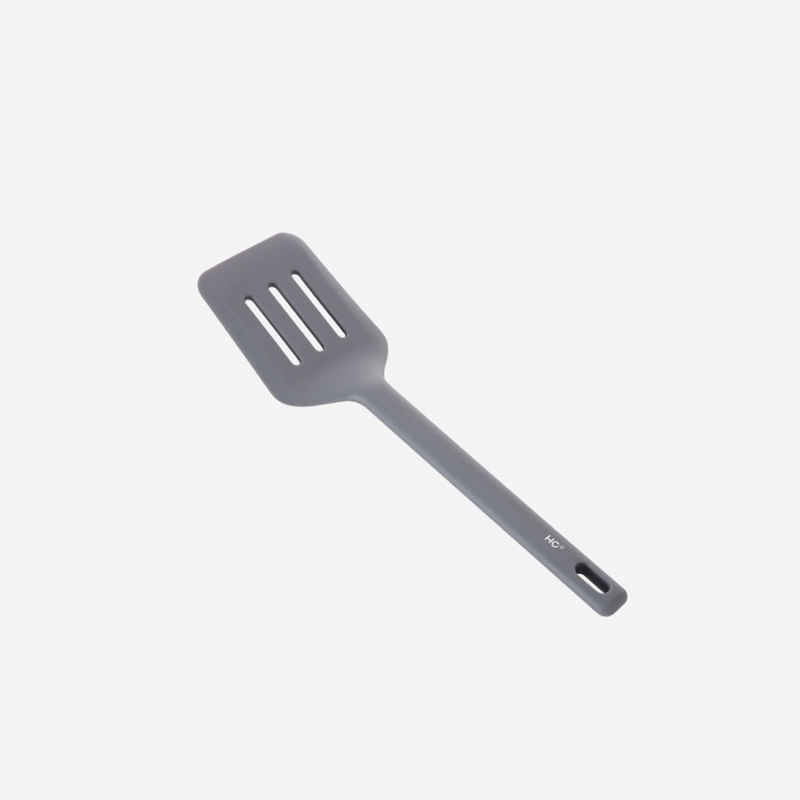 The Happycall VIVA one-piece silicone turner in dark grey, showing its wide slotted head, against a white background.
