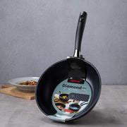 Happycall Solid Diamond nonstick induction wok 28cm standing upright in its Diamond IH packaging sleeve, with a plate of stir-fried beef on a wooden board behind.